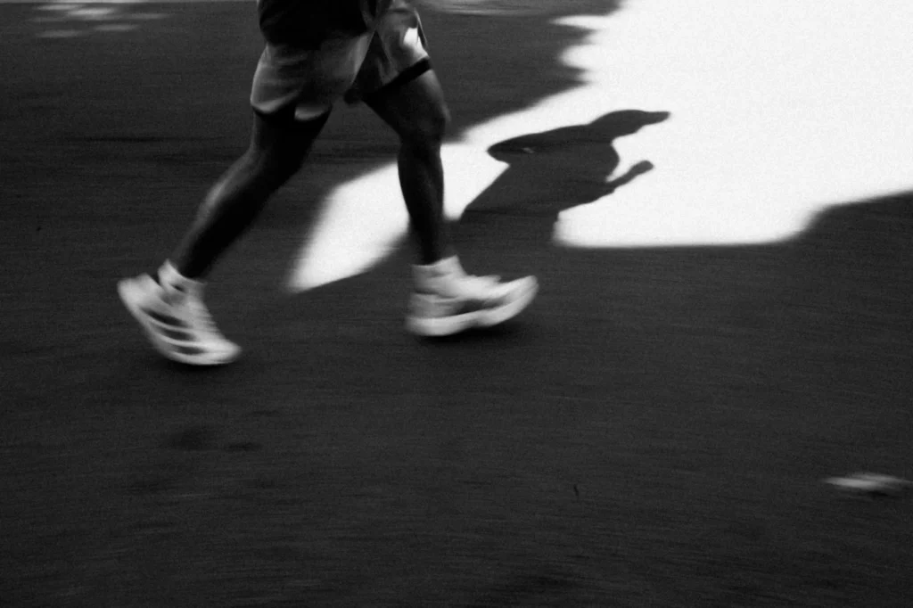 Jambes d’un coureur en mouvement et ombre sur la route